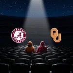 Two lone fans sit in a dim football stadium with a spotlight shining on the underdog Alabama and Oklahoma logos