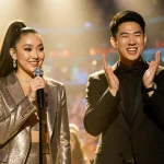 Ariana Grande holds a microphone with Bowen Yang gesturing beside her on a colorful SNL stage.