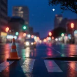 Traffic cone standing near a crosswalk with wet pavement reflecting streetlights and a dusk sky over Austin