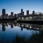 Water treatment facility standing in foreground with Austin skyline reflected in dark blue lake and vegetation indicating flo