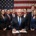 Heritage Foundation staffer stands confidently near Mike Pence with open book and American flag background.