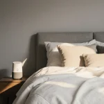 Bed presenting plush Tuft & Needle mattress with white quilt and golden bedside light