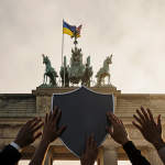 Hands forming a shield with Ukrainian and American flags above a historic Berlin building in misty morning light