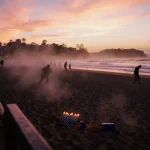 Silhouettes flee from Bondi Beach shore with sunset glow and abandoned candles