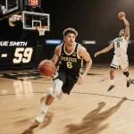 Braden Smith dribbling mid-air with Oscar Cluff shooting a three in background and scoreboard reading 79-59 near Purdue logo