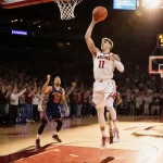Brayden Burries sinks a three-pointer with sunset scoreboard reading 96-75 and fans in background