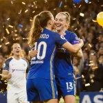 Chelsea Bronze and Sam Kerr win with confetti and balloons and a defeated Wolfsburg goalkeeper watching.