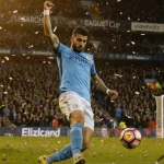Rayan Cherki takes aim shot with arms raised during Manchester City win stadium light and confetti