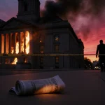 Flames licking Chicago City Hall façade with smoke billowing and a burning newspaper on sidewalk.