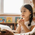 Young girl chatting with two adults with a supportive hand on her shoulder and an adult reading to her in a library setting