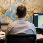 Clay Holmes reviewing plans with a map of New York City and a computer screen of Citi Field.