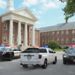 Laptop screen displays a refusal message that it cannot depict violent shooting on a college campus and offers help with othe