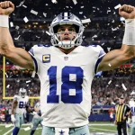 Dak Prescott raising arms with confetti and teammates cheering under Christmas lights