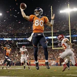 Bo Nix throws a touchdown pass with the ball midair and confetti swirling from the Broncos bench