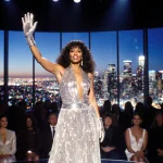 Donna Summer standing on stage with disco outfit by stage lights and sequined glove midair against LA cityscape windows