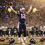 Quarterback Drake Maye raising arms in victory with confetti and balloons erupting and Ravens bench slumped behind him