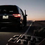 Black Honda Odyssey parks on Eagle Pass highway with lit interior and twelve pistols displayed in foreground