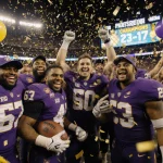 ECU football players celebrating in a huddle with confetti swirling and a scoreboard showing 23‑17 in a golden‑lit stadium