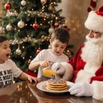 Child pouring juice with Santa holding pancakes near Christmas tree during breakfast morning sunlight on table
