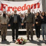 Group of activists celebrating freedom with family members holding hands in square and Freedom banner