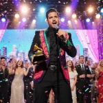 Lead singer of Grupo Frontera holds a Grammy nomination award with vibrant lights and confetti during a celebratory concert.