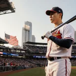 Ha-Seong Kim stands at home plate with bat slung over shoulder and Braves cap flag waves Atlanta skyline shows through roof.