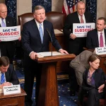 Rep. Kevin Kiley addressing lawmakers in House with tense expressions and signs and ticking clock
