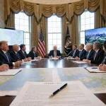 Legislators sign the SPEED Act with a pen on a wooden table surrounded by energy and infrastructure plans.