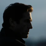 James Ransone turning away in a melancholy portrait with muted blue gray background and golden hair glow