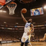 Jaylen Johnson shoots a basketball three‑pointer with Stephen Curry blocking and the scoreboard flashing 127‑120