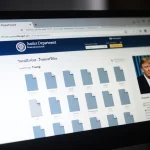 Computer screen showing Justice Department webpage with 16 empty folders and a Trump photo outline on a gray background