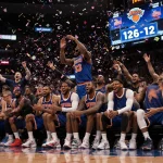 Knicks bench celebrating with Brunson and reserves high‑fiving as confetti rains and crowd cheers in Madison Square Garden