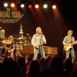 Lead singer belts out an anthem with stage lights and neon city reflections while the band plays around a vintage piano