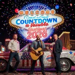 Lead singer holding guitar with neon-lit Vegas Strip and vintage car near Coast-to-Coast Countdown clock with confetti