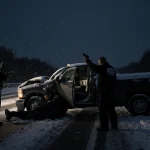 ICE officer holding gun with van driver over wheel beside pickup on Maryland highway.