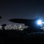 Oreshnik missile system glowing blue silhouettes against Minsk night skyline with industrial military backdrop.