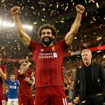 Mohamed Salah of Liverpool celebrating after scoring with teammates and confetti while Arne Slot watches proudly in golden li