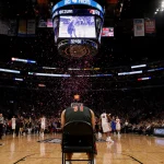 Duke player slumping over chair with scoreboard 82-81 in Madison Square Garden and Texas Tech celebrating in background.