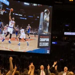 Knicks players celebrating with glowing scoreboard and jubilant fans in golden lights