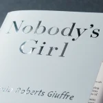 Book cover radiates soft glow with metallic title Nobody