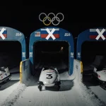 Three Russian luge sleds lying abandoned at gates with flags and X marks on crest on dim Olympic Lake Placid track