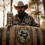 Outdoorsman standing proudly with a wooden barrel bearing Texas hunter badge camo and a limited edition Axis IPA can
