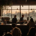Bartenders crafting cocktails with warm light and a lively crowd in Parley bar.