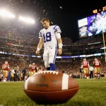 Philip Rivers walks off the field with a defeated look and a lone football beside him while the Colts 48-27 scoreboard glows.