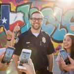 Cool Principal Buddy Bush standing before a graffiti wall with school logo and students holding phones showing Instagram vide
