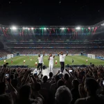 Angélique Kidjo singing with Jaylann and Lartiste amid flashing cameras and cheering fans watching Moroccan team on field
