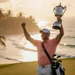 Ryan Gerard lifts a gleaming golf trophy with an ecstatic grin amid Mauritius