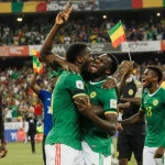 Senegal football players celebrating victory with teammates hugging and fans cheering in stadium.