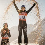 Sofia Goggia celebrates victory with confetti on podium while Lindsey Vonn applauds in background