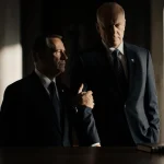 U.S. State Department official supporting a Mexican government official with a small leather-bound book in the foreground